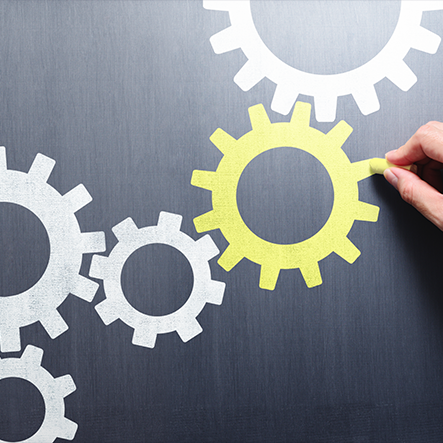 Abstract image of white gears with yellow gear highlighted